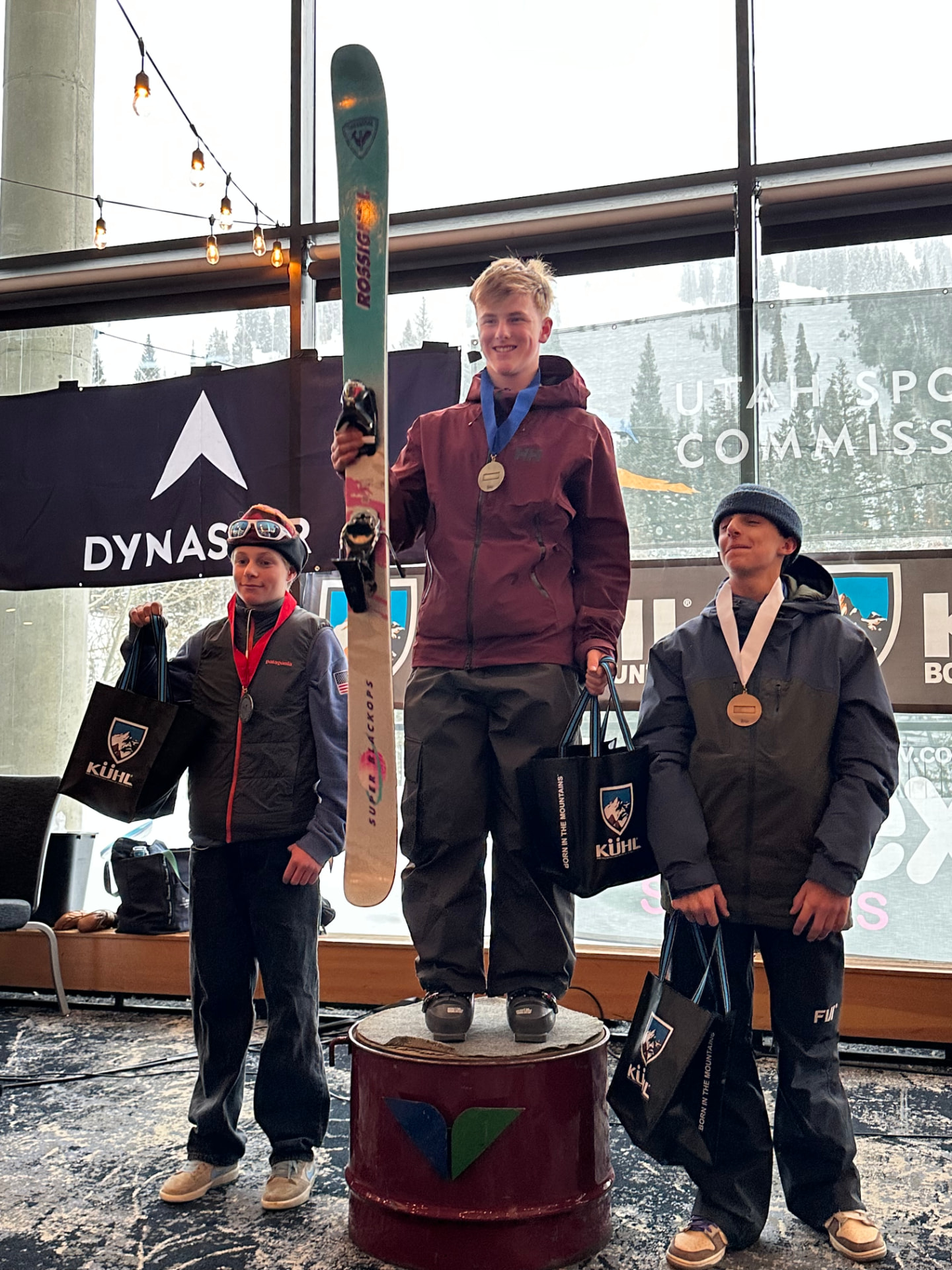 Canyon standing on the winner's podium with two fellow competitors after an awards ceremony, medals around their necks and a ski held upright