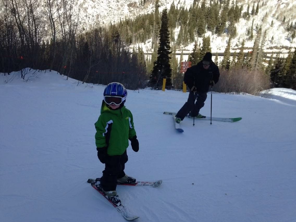 Canyon skiing downhill on his own as a young child in a green jacket